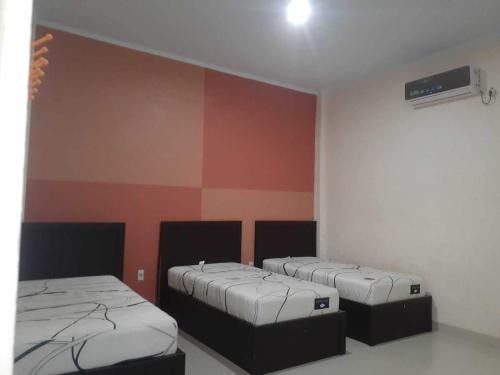 two beds in a room with red and orange walls at EXPRESS O 91662 Kost Rumah Kaca in Mirue