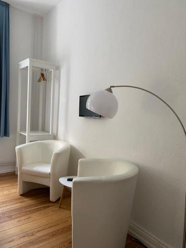 a white living room with a white chair and a lamp at Hotel Villa im Steinbusch in Malente
