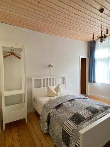 a white bedroom with a bed and a wooden ceiling at Hotel Villa im Steinbusch in Malente