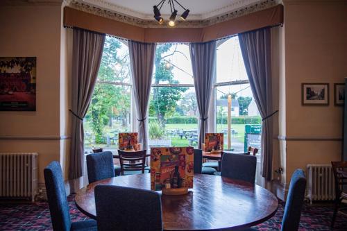 a dining room with a table and chairs and a large window at Highfield Hotel By Greene King Inn in Middlesbrough