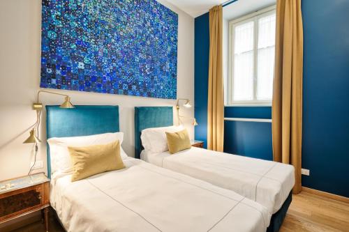 two beds in a room with a painting on the wall at Palazzo Del Carretto-Art Apartments and Guesthouse in Turin