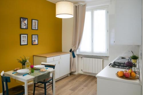 a kitchen with yellow walls and a table and a kitchen with a stove at Residence Ferraud in Pinerolo