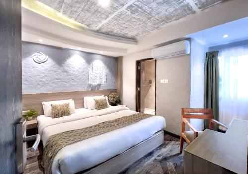 ein Hotelzimmer mit einem großen Bett und einem Schreibtisch in der Unterkunft Vastu Boutique Hotel in Kathmandu