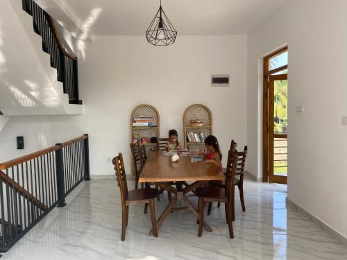 2 enfants assis à une table en bois dans une salle à manger dans l'établissement The Pearl, à Marawila