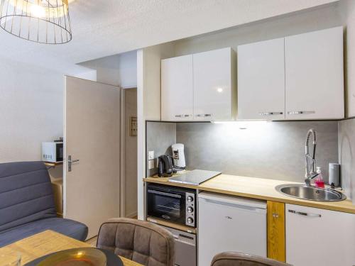 une cuisine avec des armoires blanches, une table et un évier dans l'établissement Studio 4 pers - Pied télécabines - Parking - Équipé - WIFI - FR-1-401-208, à Cauterets