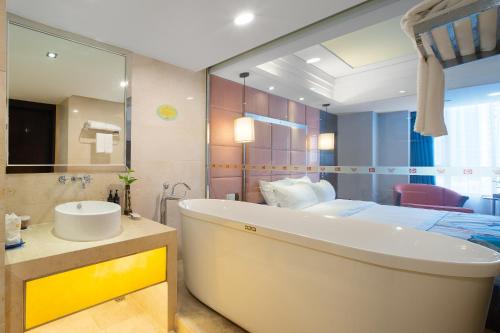 ein Bad mit einer Badewanne, einem Waschbecken und einem Bett in der Unterkunft Foshan Rezen Select Pasonda Hotel in Foshan