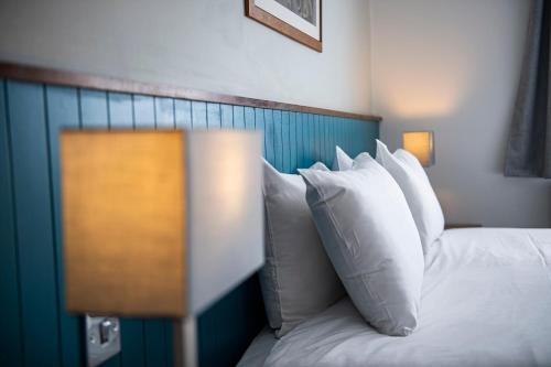 a bed with white pillows and a blue head board at Highfield Hotel By Greene King Inn in Middlesbrough
