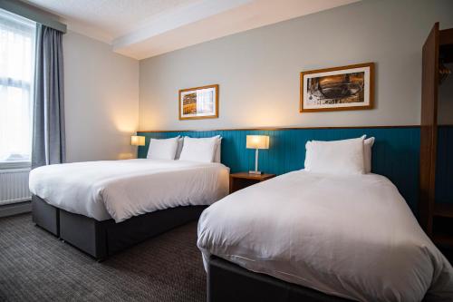 a hotel room with two beds and a window at Highfield Hotel By Greene King Inn in Middlesbrough