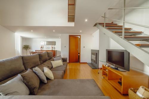a living room with a couch and a television at OPORTO GUEST Oliveira House in Porto