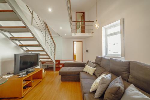 a living room with a couch and a television at OPORTO GUEST Oliveira House in Porto