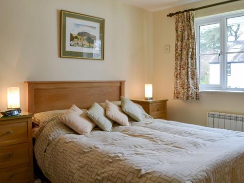 ein Schlafzimmer mit einem Bett mit Kissen und einem Fenster in der Unterkunft Meadowcroft Cottage in Bowness-on-Windermere