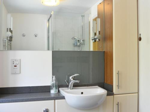 ein Badezimmer mit einem weißen Waschbecken und einer Dusche in der Unterkunft Meadowcroft Cottage in Bowness-on-Windermere