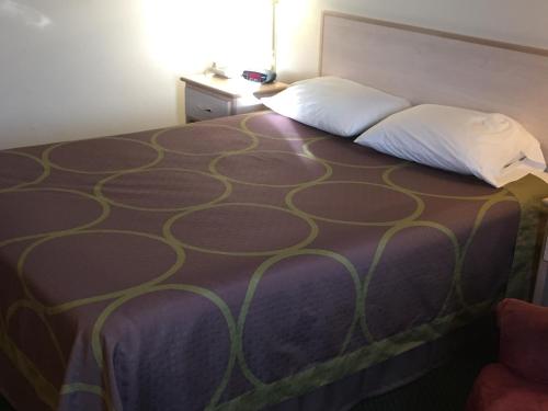 a bed in a hotel room with a large bedskirtspectspectspects at Super 8 by Wyndham Willcox in Willcox