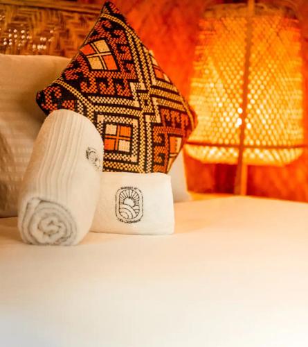 a pillow on a bed with a house on it at Sunset at Las Cabanas in El Nido