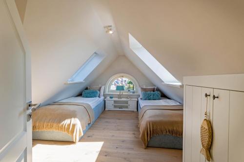um quarto no sótão com 2 camas e uma janela em Ferienhaus SylterLiebe em Tinnum