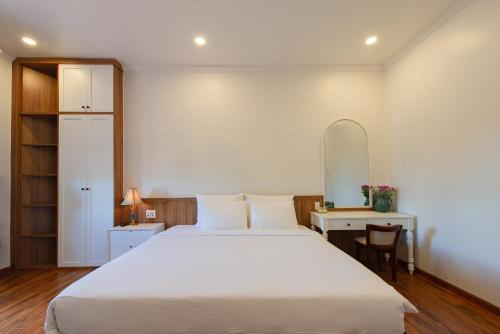 a bedroom with a large white bed and a desk at Le Soleil Boutique Hotel in Da Lat