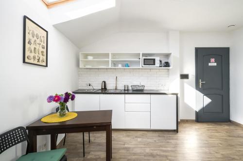una cucina con armadi bianchi e un tavolo con fiori di Modern aparment in the very central location 19 a Cracovia