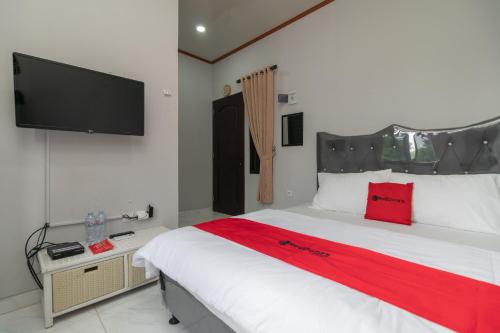 a bedroom with a large bed with a flat screen tv at RedDoorz Plus near Jungeland Sentul in Bogor