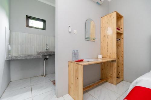 a bathroom with a wooden door and a sink at RedDoorz Plus near Jungeland Sentul in Bogor