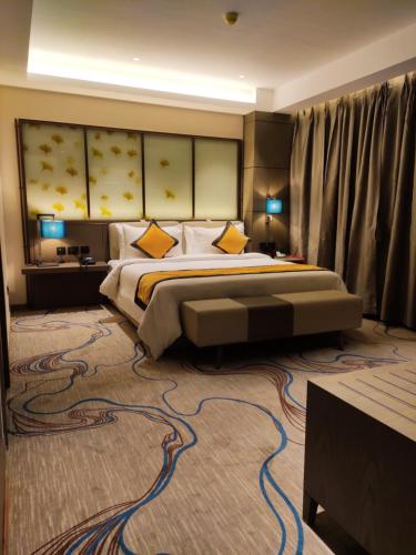 a large bedroom with a large bed with yellow pillows at Sunhill Portico in Siliguri
