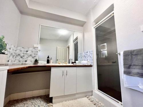 uma casa de banho com um lavatório e um espelho grande em Tastefully renovated - 3 bedroom apartment em South Hedland