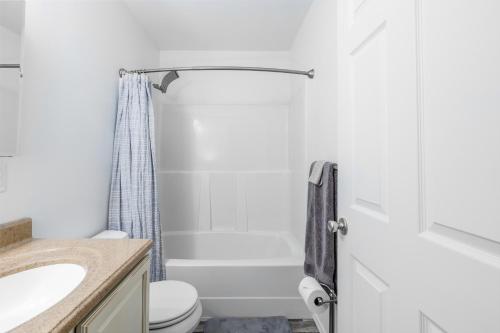 Baño blanco con aseo y lavamanos en AlohAlaska Upstairs Suite, en Girdwood