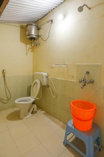 a bathroom with a toilet and a bucket in it at DEVASHOLA HOMESTAY in Coonoor