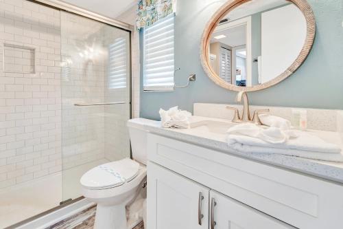 W łazience znajduje się umywalka, toaleta i lustro. w obiekcie Coquina Reef 11 w mieście Bradenton Beach