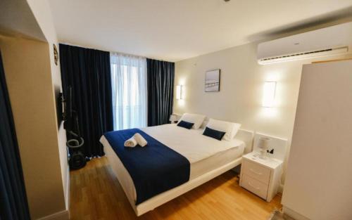 a bedroom with a large white bed with a blue blanket at View & More Aparthotel in Batumi in Batumi