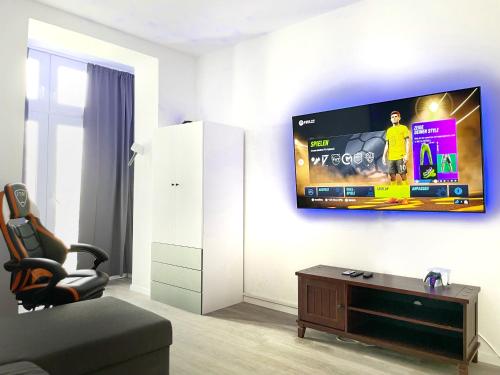 ein Wohnzimmer mit einem Flachbild-TV an der Wand in der Unterkunft Gaming PS5 + 65 Zoll 4K TV Wohnung mit Balkon in Dortmund
