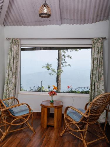 a living room with chairs and a large window at DEVASHOLA HOMESTAY in Coonoor