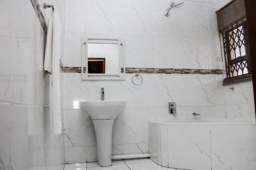 a white bathroom with a sink and a bath tub at Tshukudu e Ntsho in Mogwase