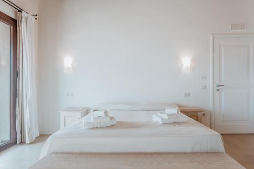 a white bedroom with a bed and a window at Resort Fior di Sardegna in Posada