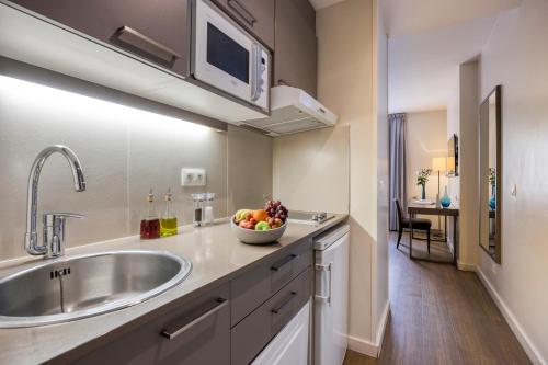 uma cozinha com um lavatório e uma taça de fruta no balcão em Citadines Toison d’Or Brussels Aparthotel em Bruxelas