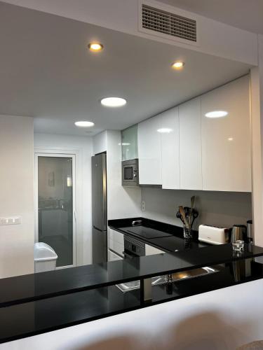 a kitchen with white cabinets and a black counter top at Flamenca Village by Mar Holidays in Orihuela Costa