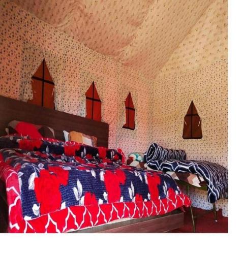 a bedroom with two beds with colorful blankets and pillows at Camping at Serene Chopta in Sari