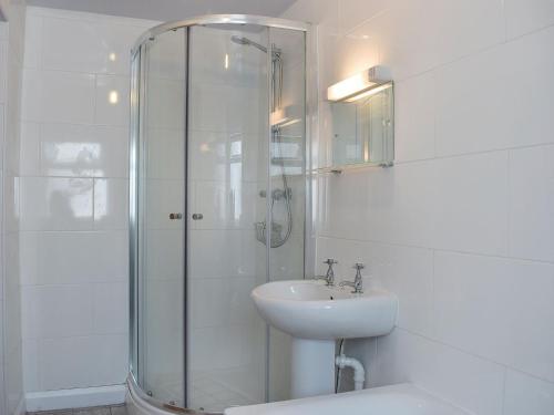 a white bathroom with a shower and a sink at Alice Cottage in Embleton