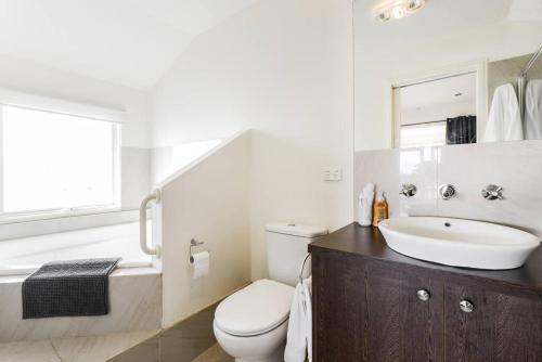 La salle de bains est pourvue de toilettes, d'un lavabo et d'une baignoire. dans l'établissement By The Seaside, à Mornington