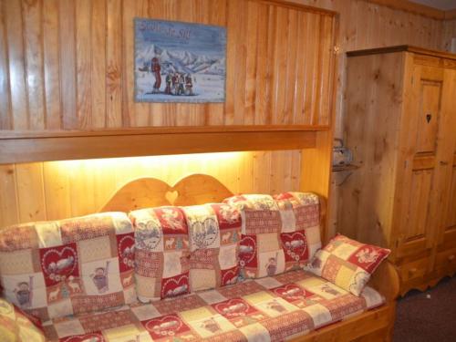 ein Sofa in einem Zimmer mit einer Holzwand in der Unterkunft Studio Les Menuires, 1 pièce, 2 personnes - FR-1-452-11 in Les Menuires