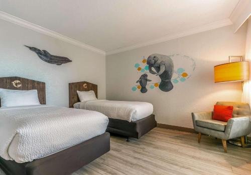 um quarto de hotel com duas camas e uma cadeira em Winter the Dolphin's Beach Club, Ascend Hotel Collection em Clearwater Beach