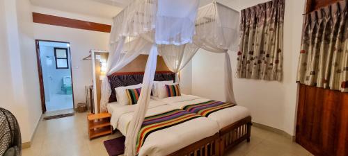 a bedroom with a bed with a canopy at Hilltop Guest House in Ella