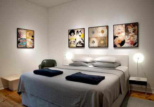 a bedroom with a large bed with four pictures on the wall at New Art Apartment in Lisbon