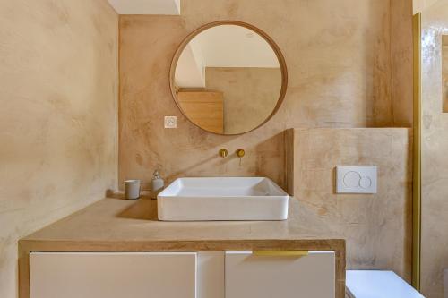 uma casa de banho com um lavatório branco e um espelho. em Appartement parisien lumineux proche métro em Clichy