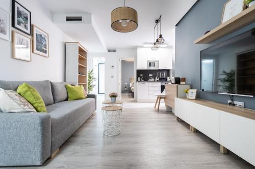 a living room with a couch and a kitchen at Apartamento Mani en Avenida España con terraza in Albacete