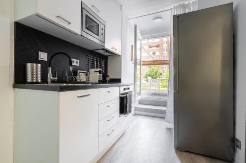 a kitchen with white cabinets and a black wall at Apartamento Mani en Avenida España con terraza in Albacete