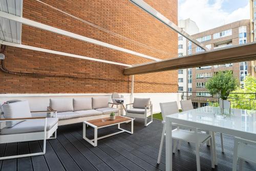 a rooftop patio with white furniture and a brick wall at Apartamento Mani en Avenida España con terraza in Albacete