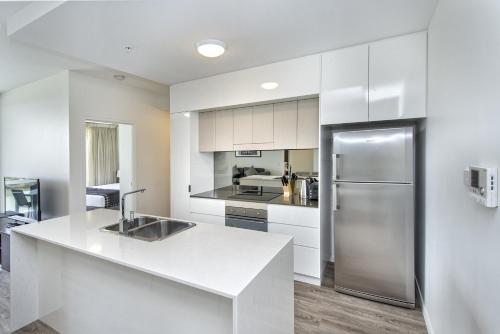 a kitchen with white cabinets and a stainless steel refrigerator at Empire Apartment Hotel Rockhampton in Rockhampton