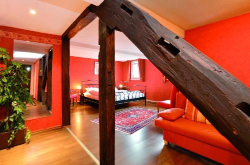 ein Zimmer mit roten Wänden und ein Schlafzimmer mit einem Bett in der Unterkunft Hotel Stoffels in Schmallenberg