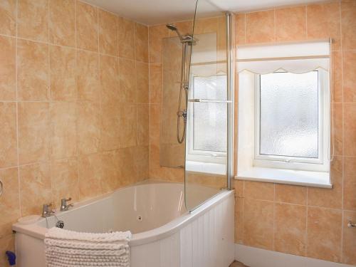 a bathroom with a bath tub and a window at Writers Cottage - Uk33475 in Nenthead