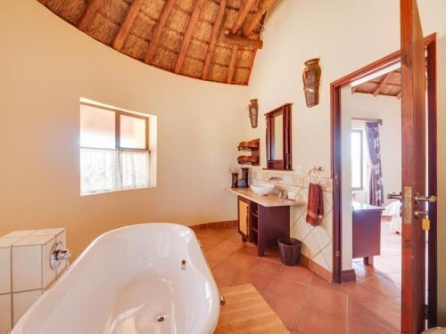 ein großes Badezimmer mit Badewanne und Waschbecken in der Unterkunft Luxurious 4 Bedroom Villa with Cottage 205 in Mabula